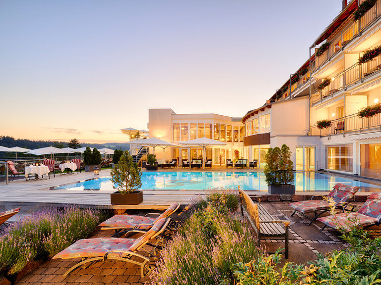 Der großzügige Outdoorpool mit Liegemöglichkeiten lässt keine Wünsche offen. Außenpool mit Sonnenliegen und Teil des Wellnesshotels.