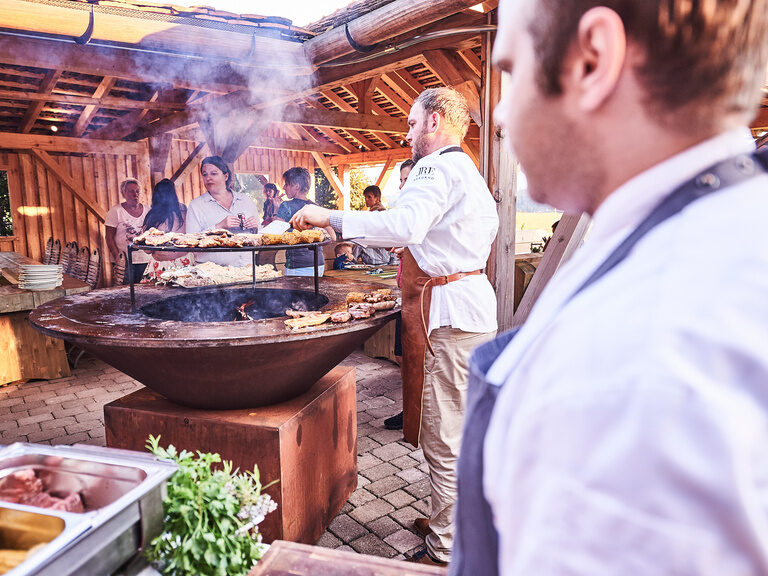 Das Biberschwanzdächle des Zavelsteiner Wanderheims eignet sich hervorragend für Grillevents. Zwei Köche stehen an einem großen Grill und bereiten, im Rahmen einer Feierlichkeit, leckere Grillspezialitäten zu.