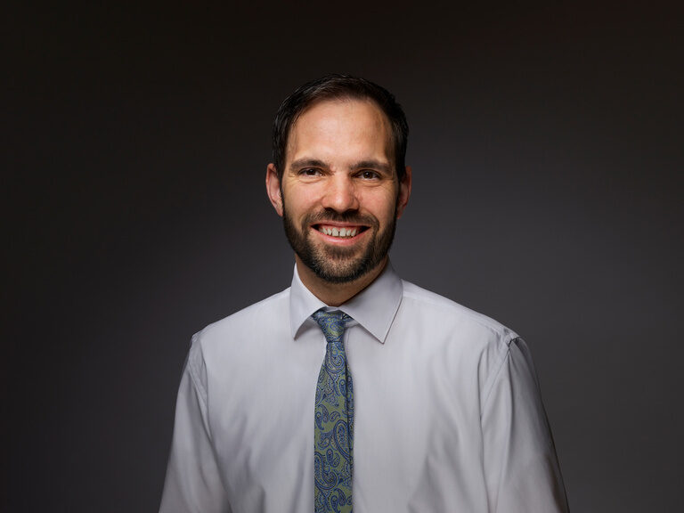 Der Juniorchef des Hotels KroneLamm, Roland Berlin, posiert entspannt vor einem schwarzen Hintergrund.