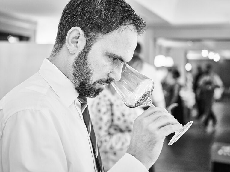 Nahaufnahme des Someliers und Juniorchefs Roland Berlin bei der Weinprobe.